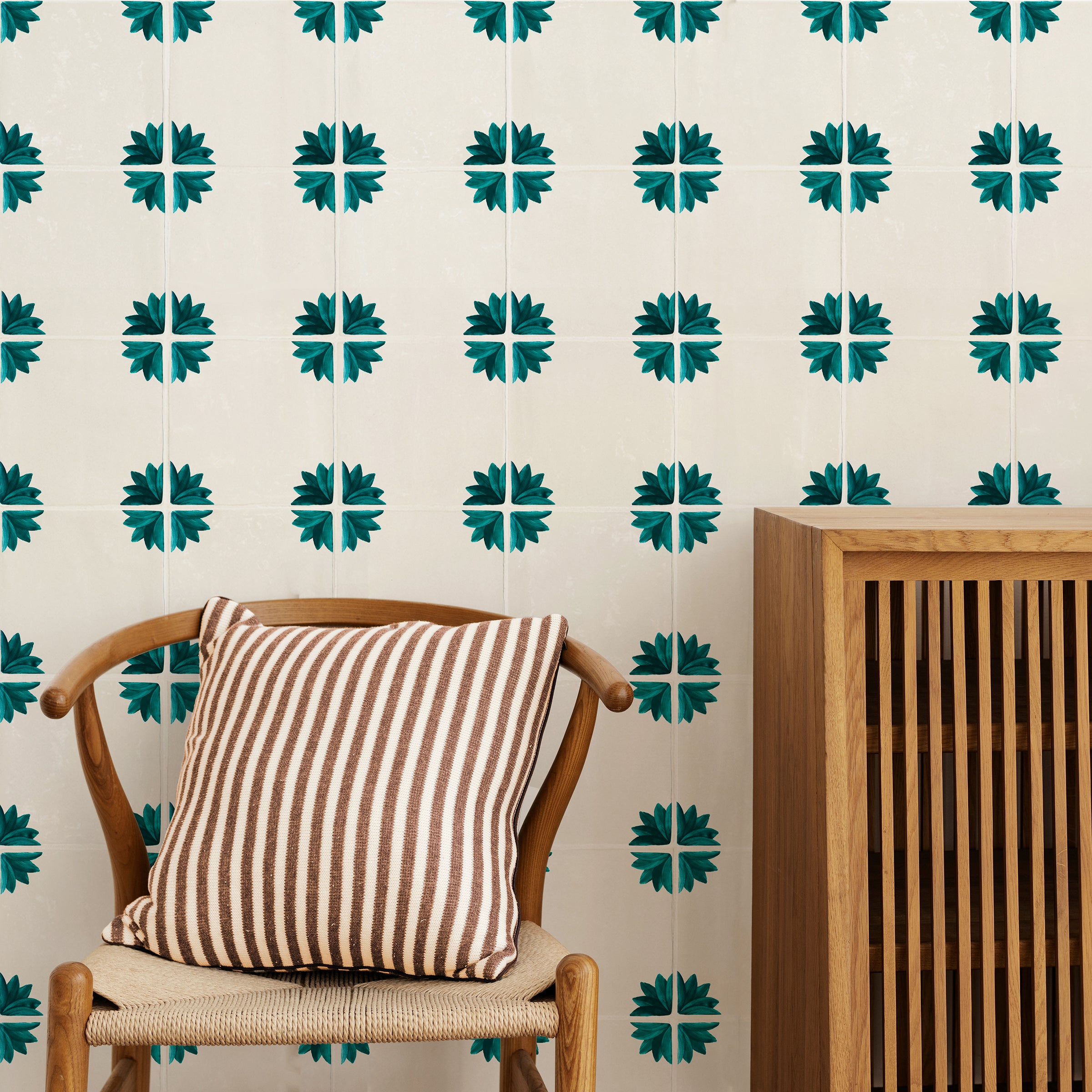 Chair with striped pillow against a wall with decorative floral green tiles.