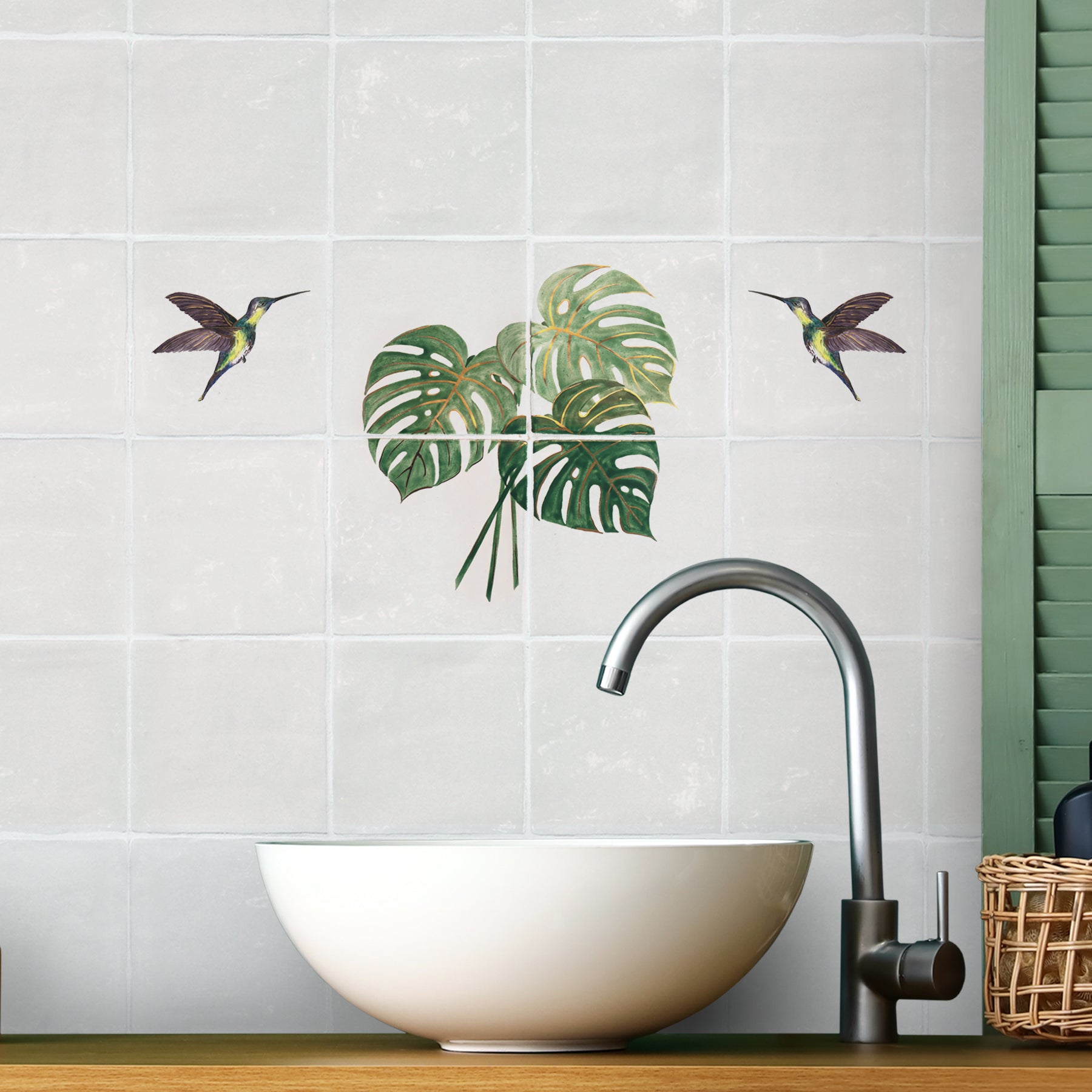 Monstera leaf panel and purple hummingbirds tiled above bathroom sink