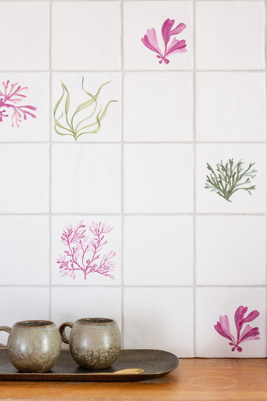 Decorative wall tiles with seaweed designs on a tiled wall.