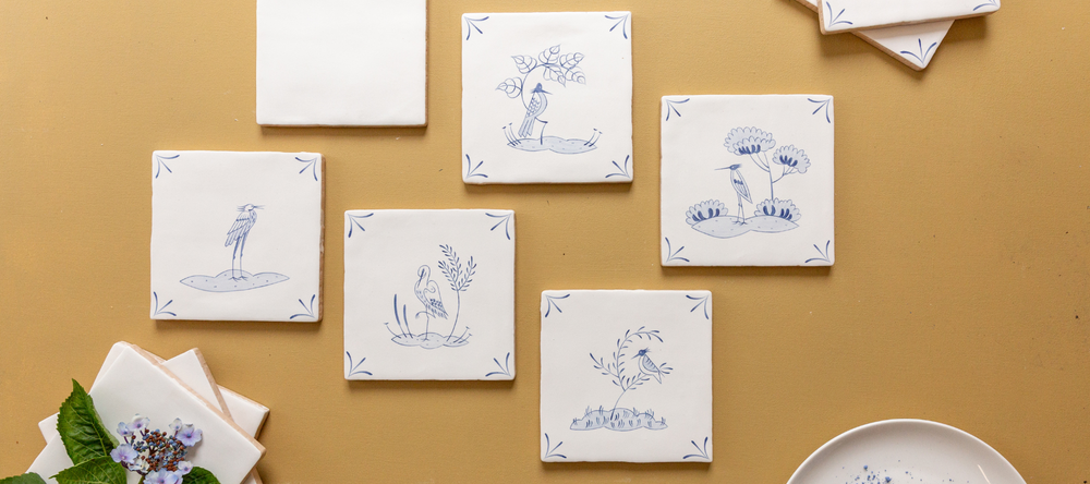 Set of decorative blue delft tiles with illustrations on a beige background