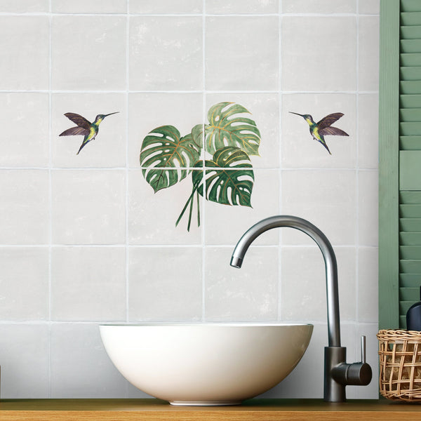Monstera leaf panel with hummingbird tiles above bathroom sink
